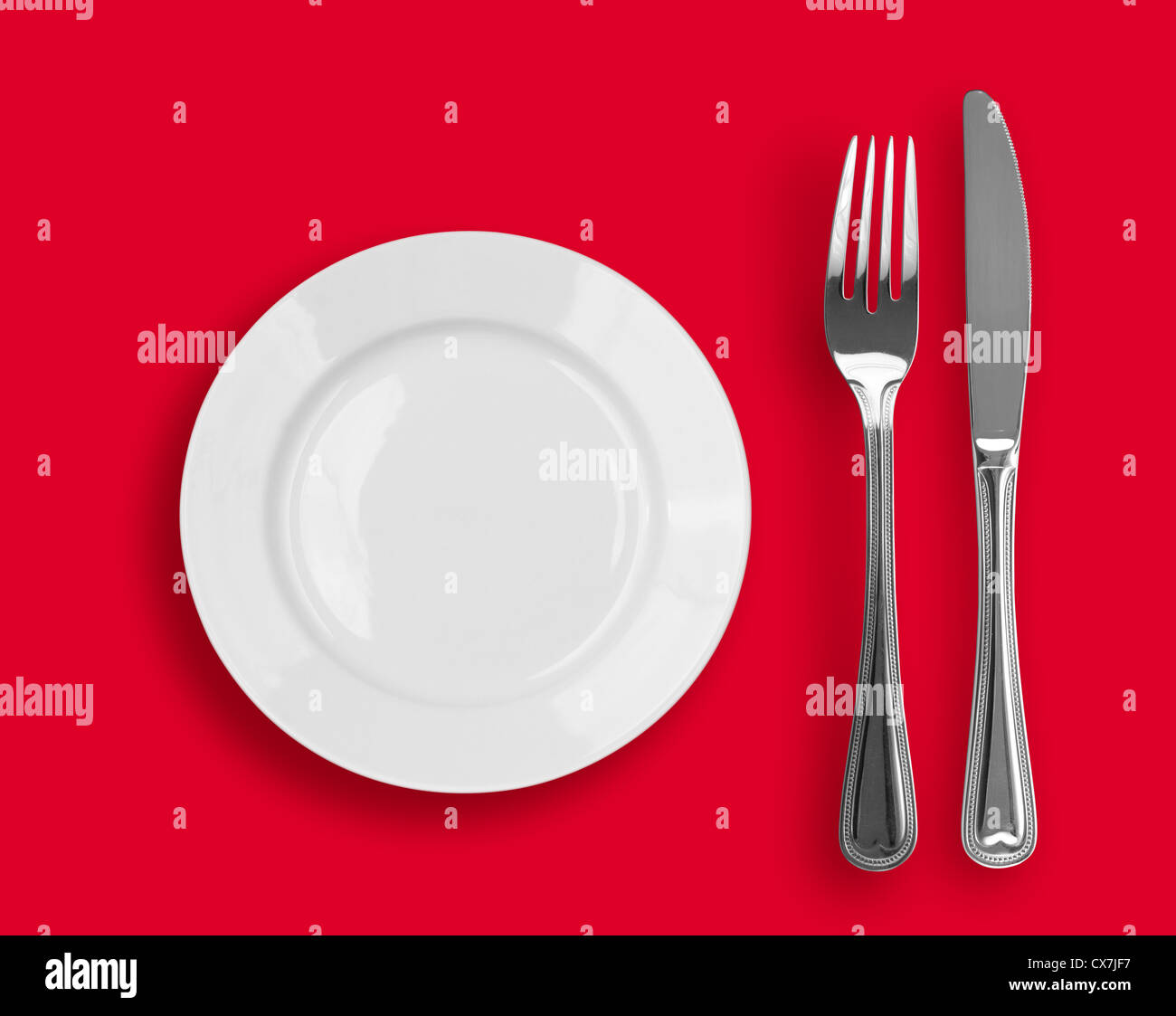 Coltello, piastra bianca e forcella su sfondo rosso Foto Stock