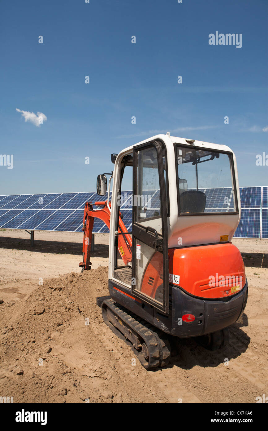 Escavatore su pannello solare sito in costruzione Foto Stock