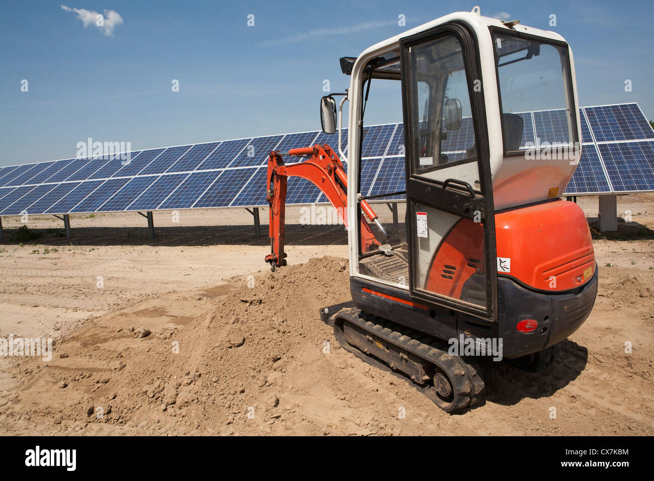 Escavatore meccanico sul pannello solare sito in costruzione Foto Stock