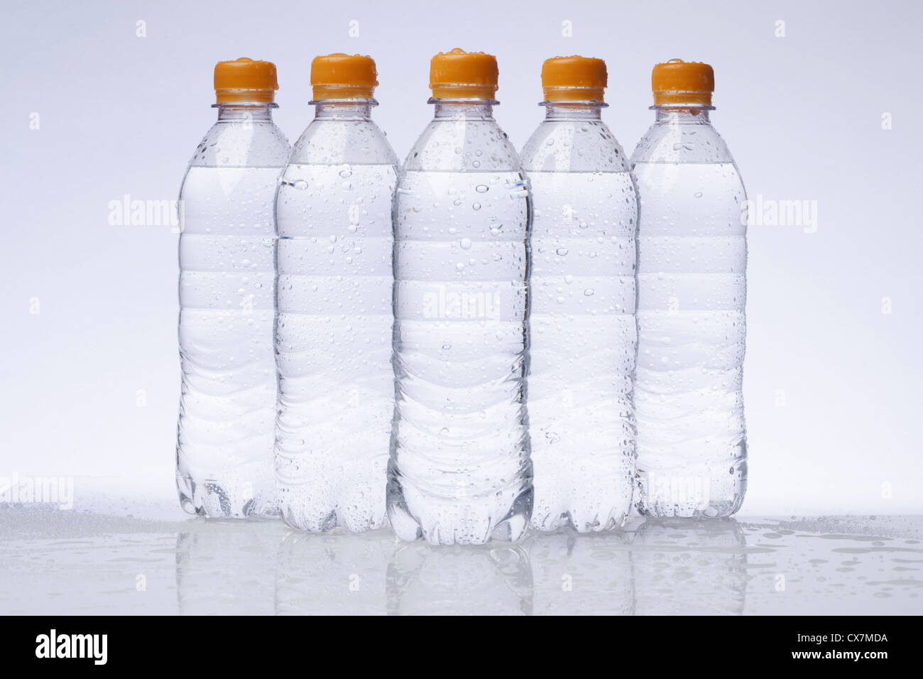 Una fila di cinque pieno di acqua in plastica bottiglie disposte in una forma a piramide Foto Stock
