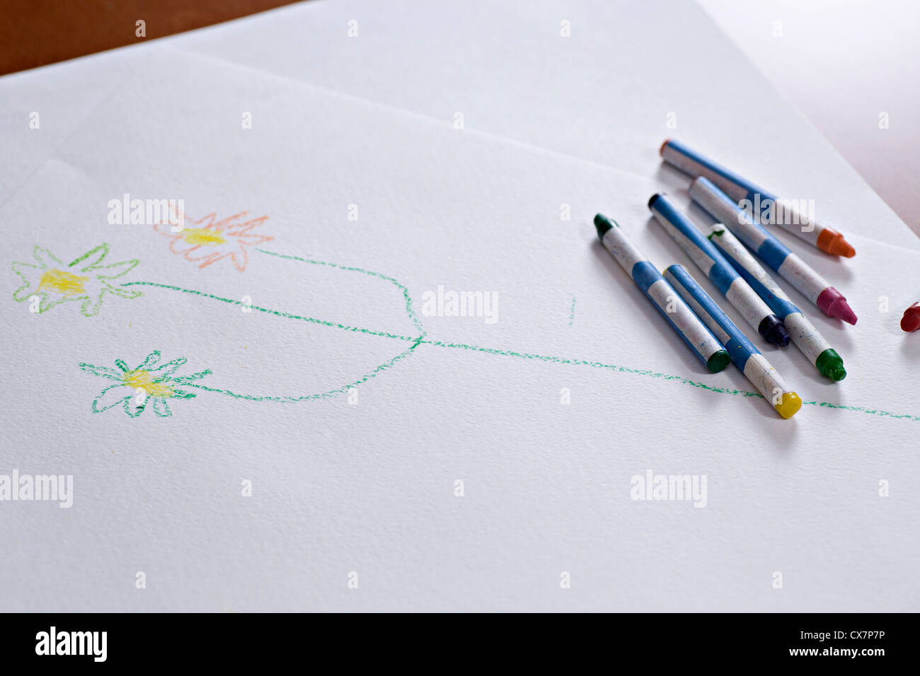 Crayons giacente su un bambino il disegno di uno stelo con fiori su di esso Foto Stock