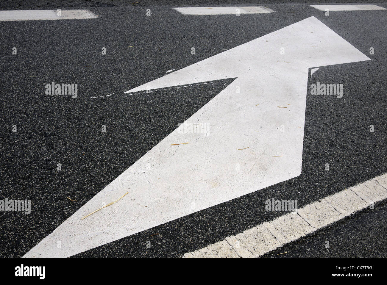Freccia bianca dipinta su una strada. Foto Stock