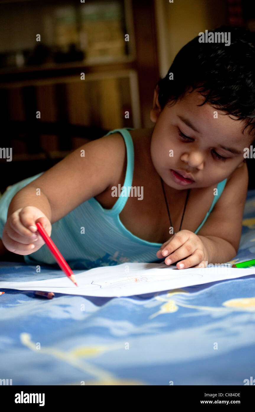 Una ragazza indiana è il disegno con le matite colorate che stabilisce nel suo letto Foto Stock