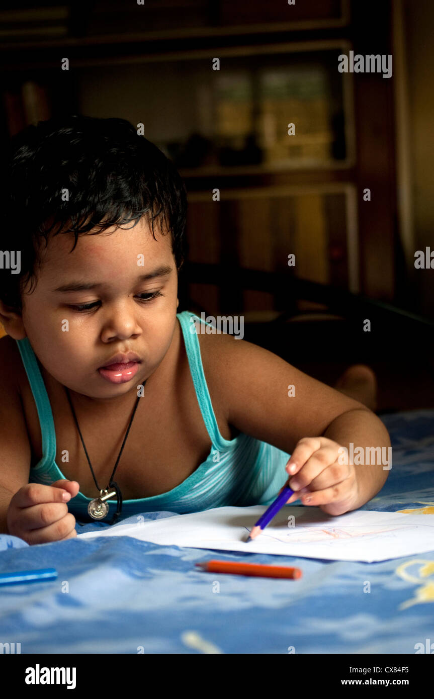 Una ragazza indiana è il disegno con le matite colorate che stabilisce nel suo letto Foto Stock