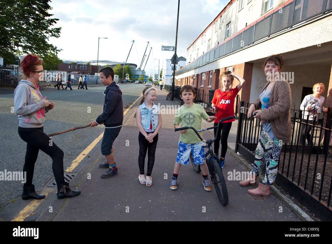 I bambini giocano sul ciglio della strada accanto al famigerato Beswick station wagon, East Manchester, Inghilterra, Regno Unito Foto Stock