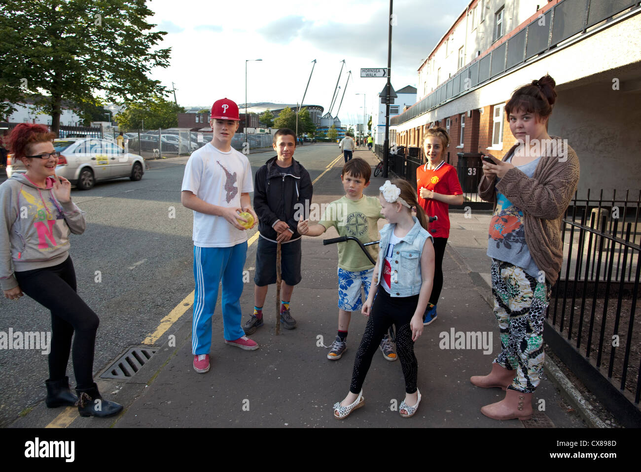 I bambini giocano sul ciglio della strada accanto al famigerato Beswick station wagon, East Manchester, Inghilterra, Regno Unito Foto Stock
