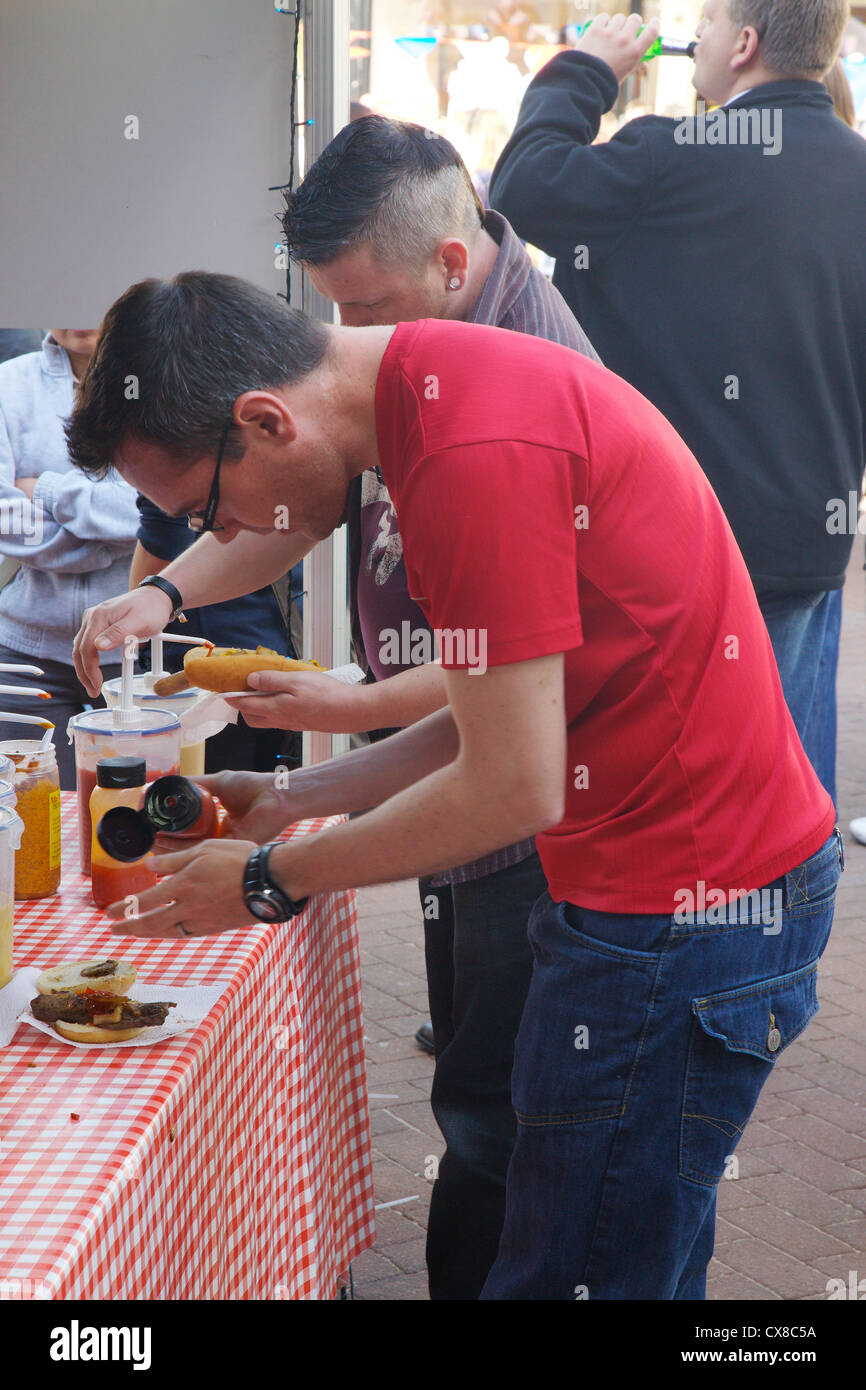 L'uomo mettendo fonte marrone su un hamburger a Carlisle celebrazioni giubilari nel centro di Carlisle Cumbria, England Regno Unito Foto Stock