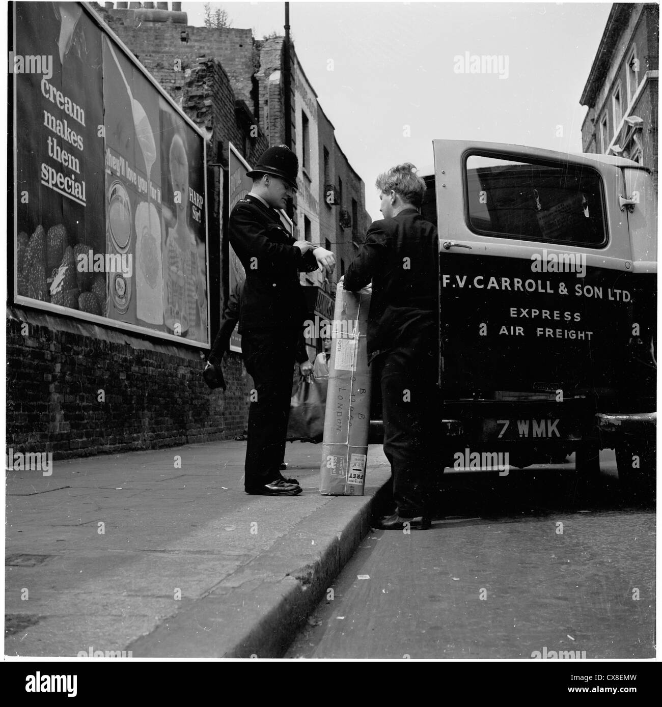 Londra,1950s. Poliziotto parla di una consegna di pacchi l uomo al di fuori del suo furgone, mentre si verifica il suo orologio per vedere quanto tempo egli gli darà a lasciare sulla strada mentre egli fa la sua consegna. Foto Stock