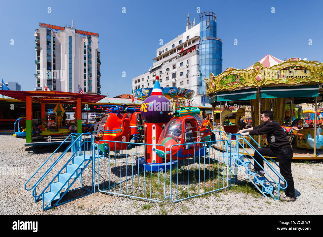 Una giostra e un piccolo parco di divertimenti da università albanese edificio nel centro di Tirana, Albania Foto Stock