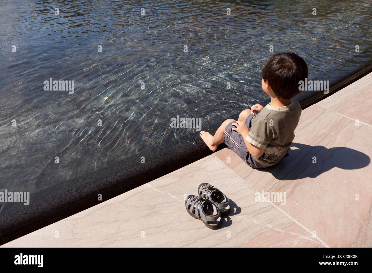 Ragazzo asiatico in seduta pubblica fontana Foto Stock