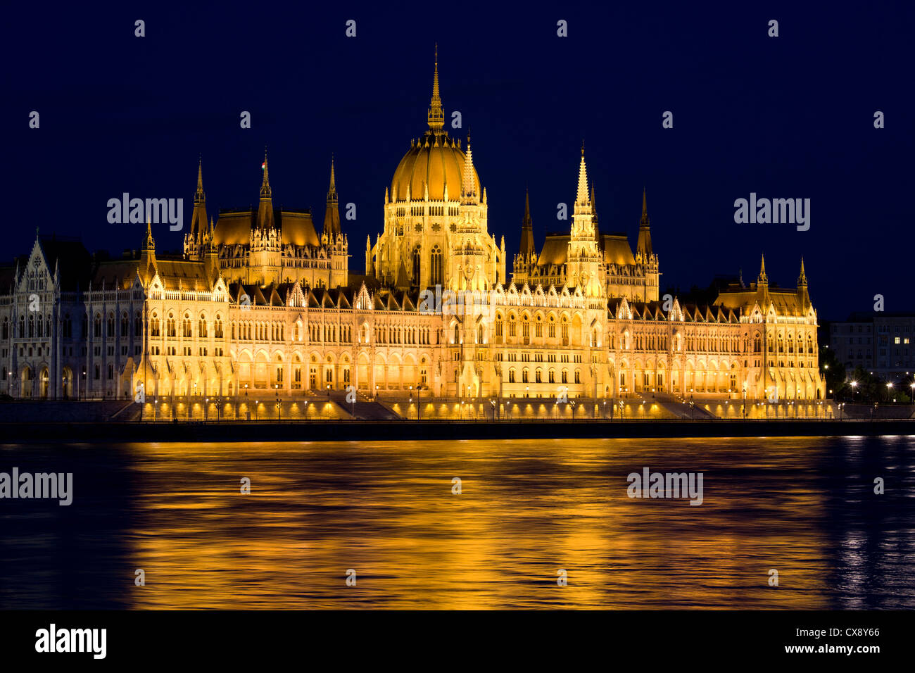 Il Parlamento di Budapest in Ungheria di notte, le riflessioni sul fiume Danubio acque. Foto Stock