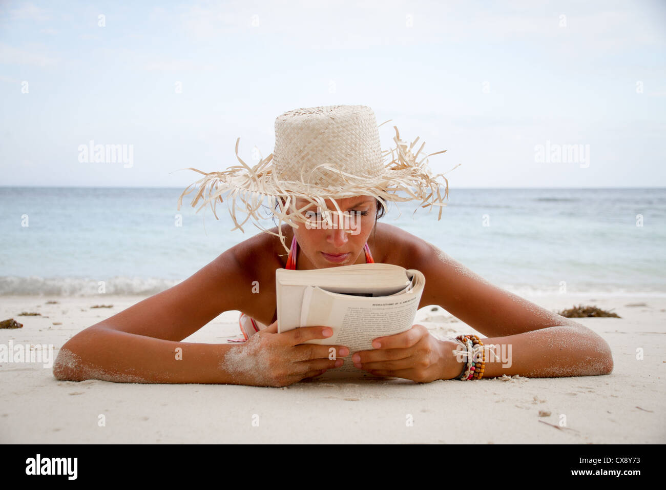 Giovane donna sulla spiaggia libro di lettura Foto Stock