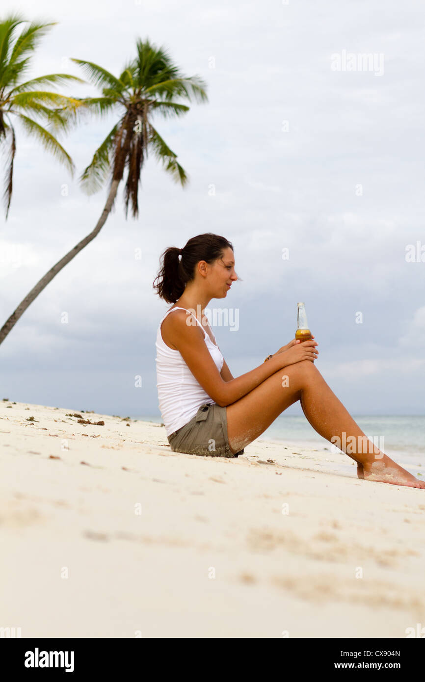 Giovane donna con la birra sulla spiaggia Foto Stock