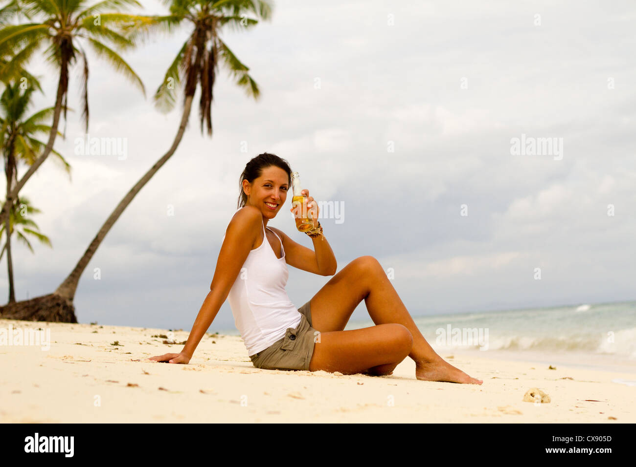 Giovane donna con la birra sulla spiaggia Foto Stock