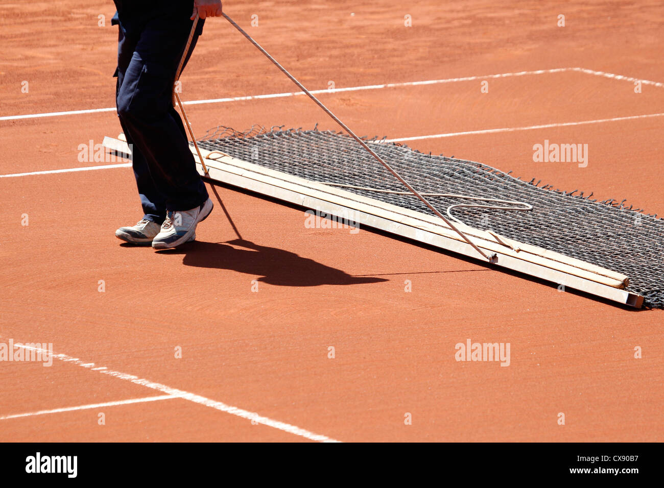 Levigatura di argilla sul campo da tennis con una spazzatrice Foto Stock