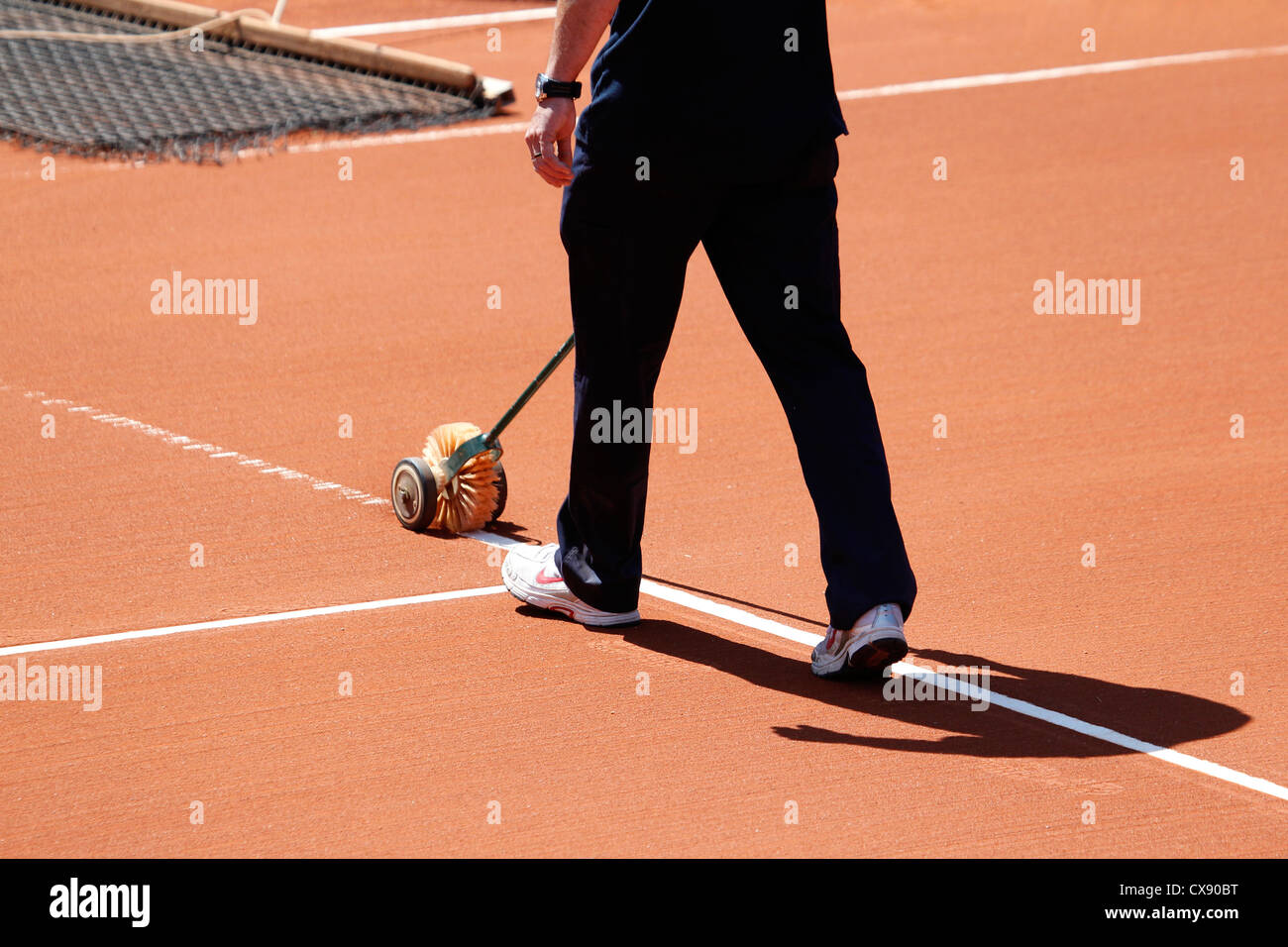 Levigatura di argilla sul campo da tennis utilizzando una spazzola a rullo Foto Stock