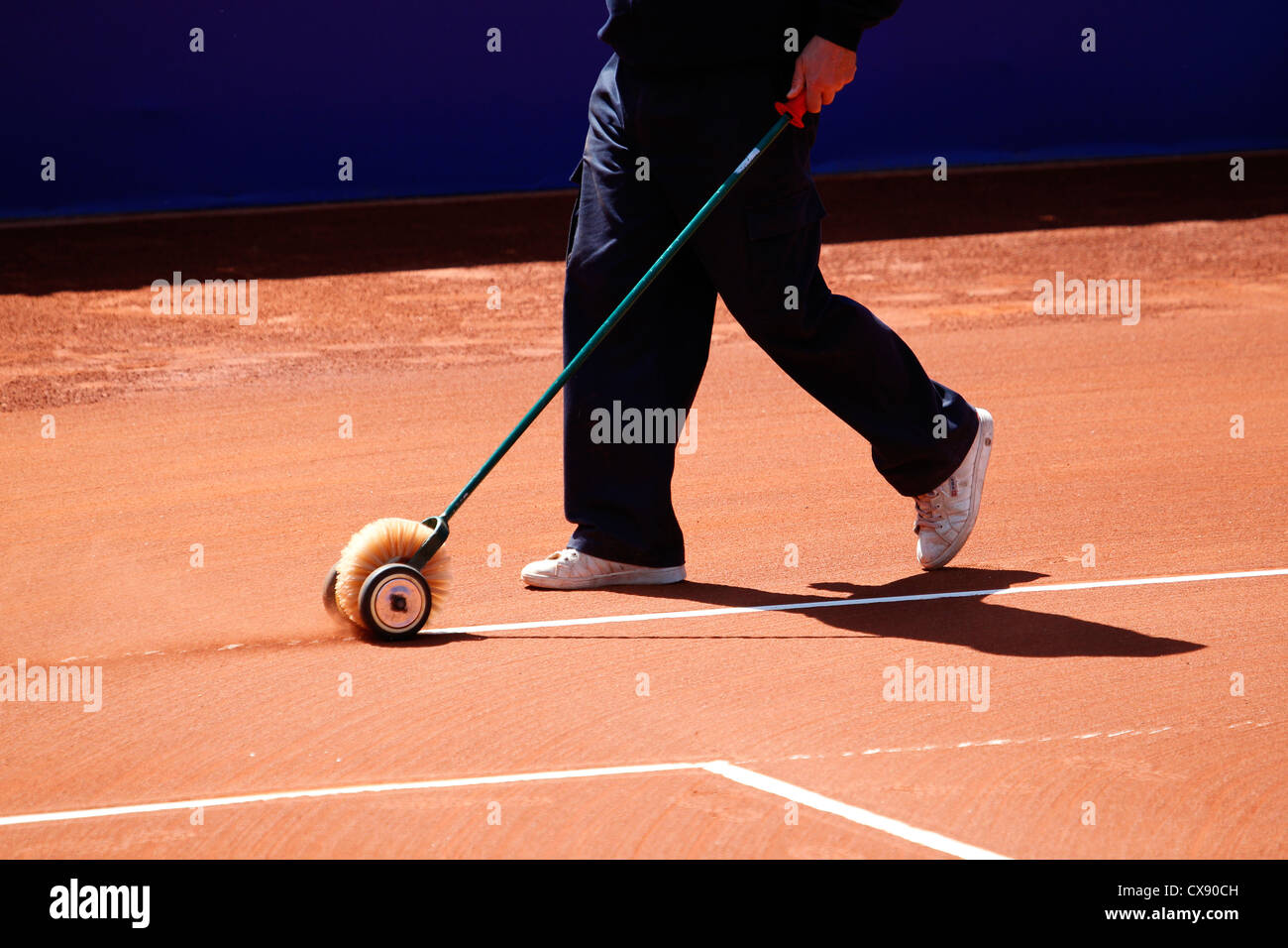 Levigatura di argilla sul campo da tennis utilizzando una spazzola a rullo Foto Stock