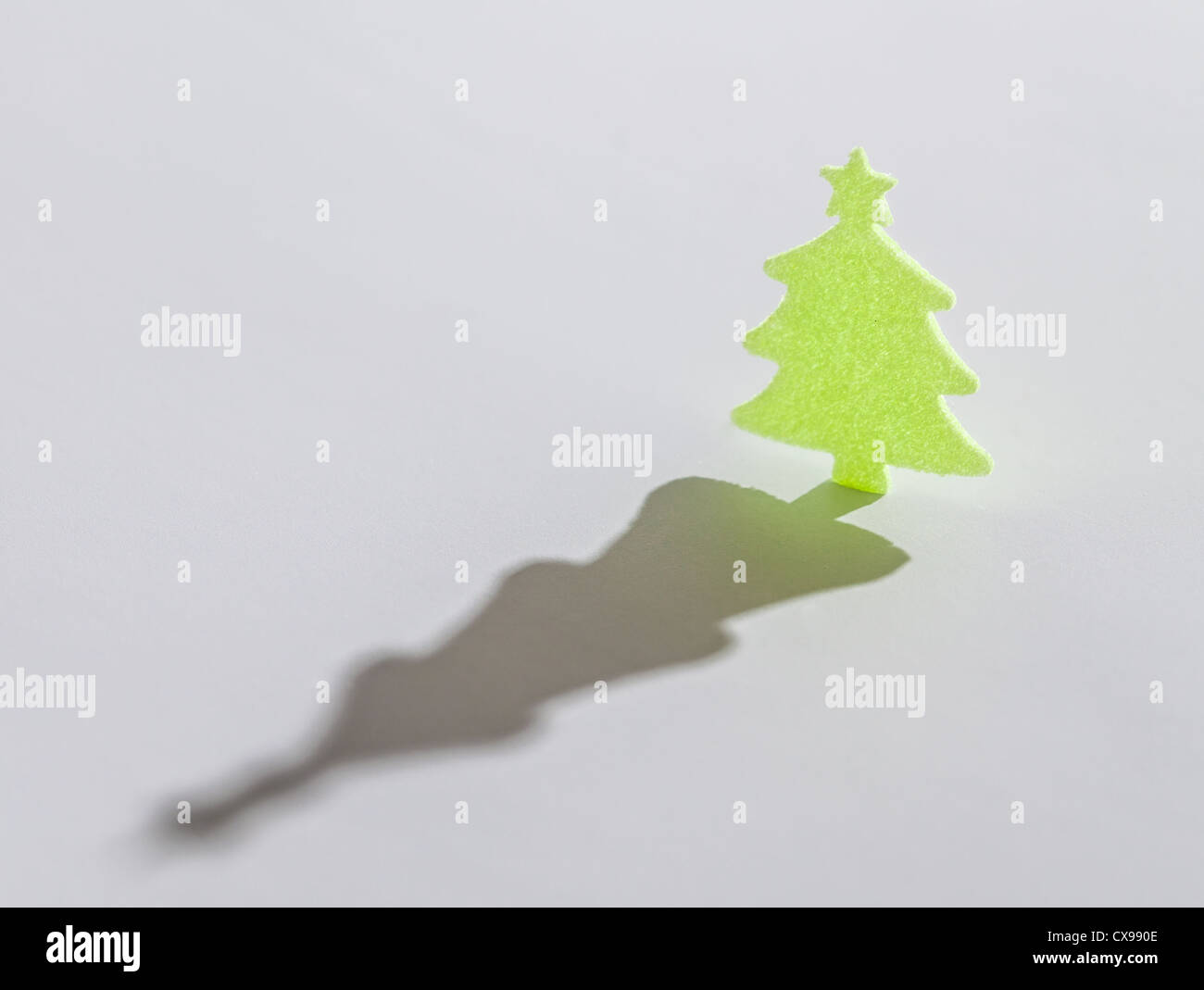 Piccolo verde albero di natale con lunga ombra su sfondo bianco Foto Stock