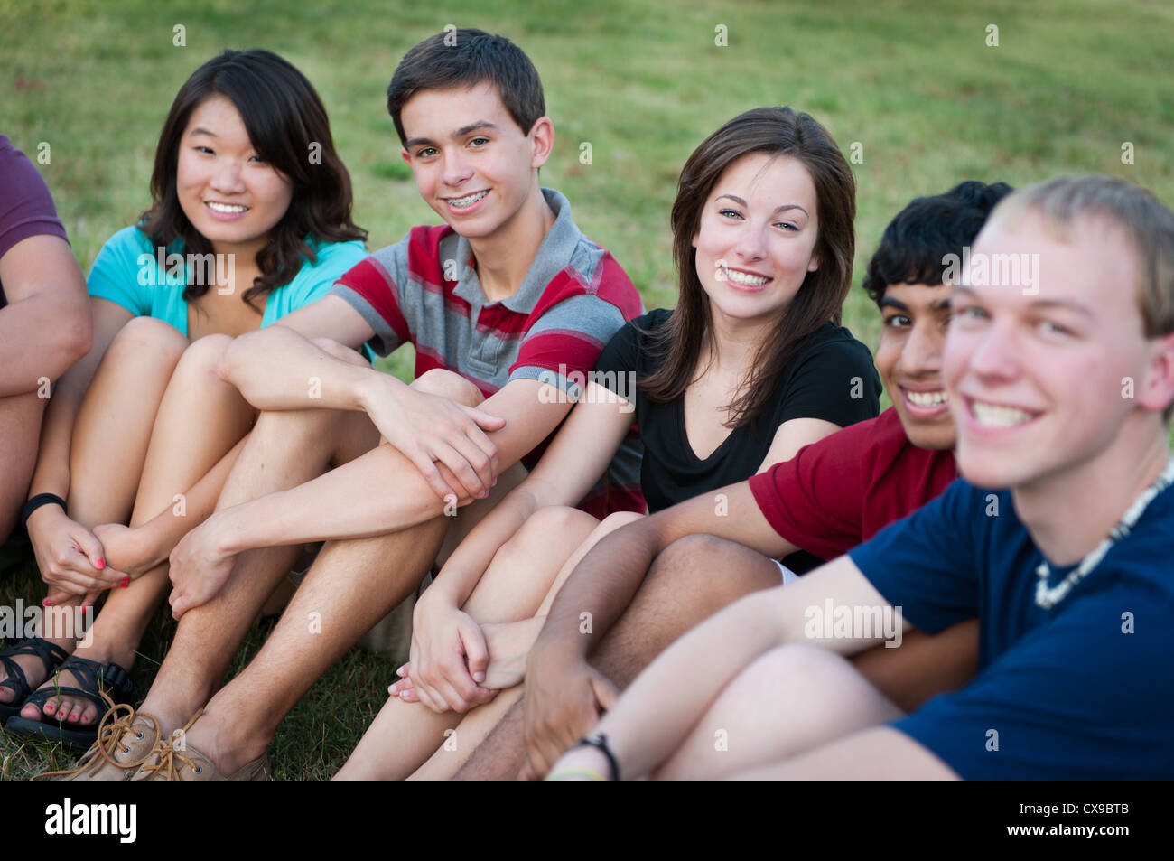 Variegato gruppo di amici al di fuori sorridente Foto Stock