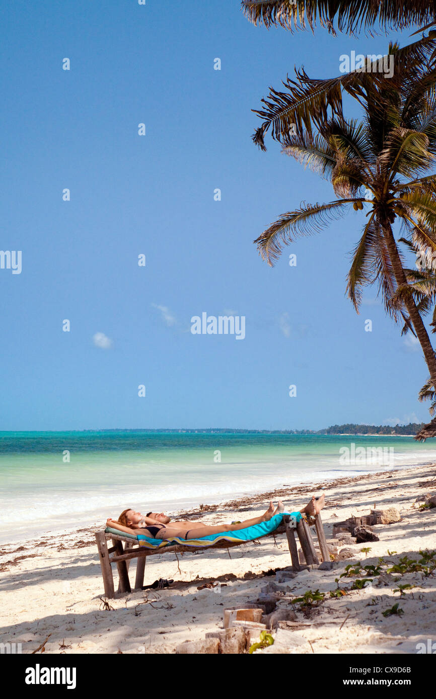 Coppia giovane a prendere il sole sulla spiaggia a Bjewuu, Zanzibar Africa Foto Stock