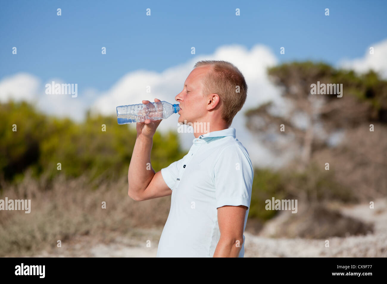 Giovane uomo ist acqua potabile estate spiaggia di dune sullo sfondo del cielo Foto Stock