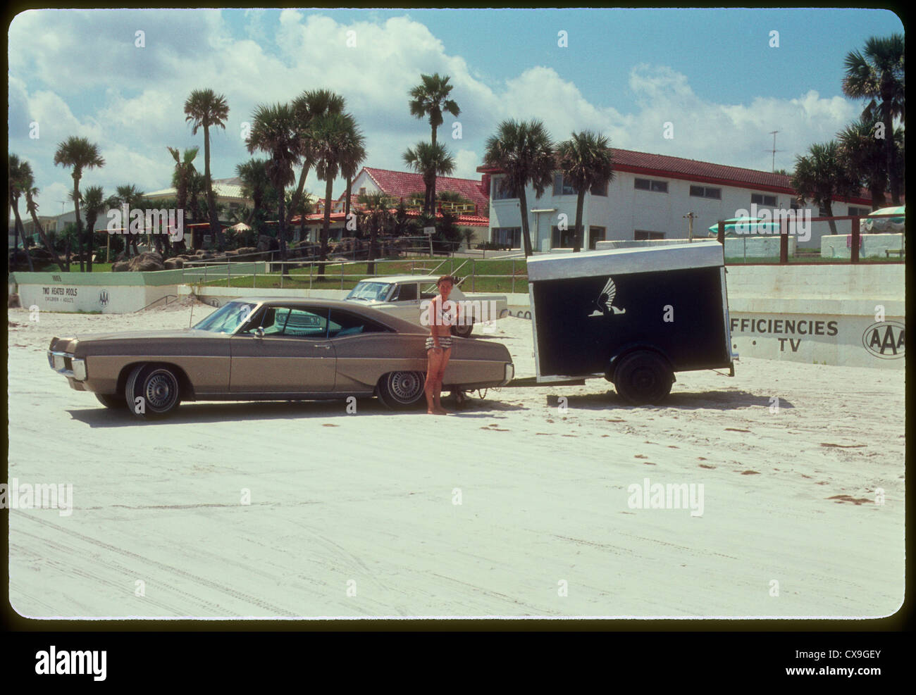 Donna in piedi su daytona beach accanto alla vettura 1968 anni sessanta bikini vacanze estive turistiche della Florida turismo Foto Stock