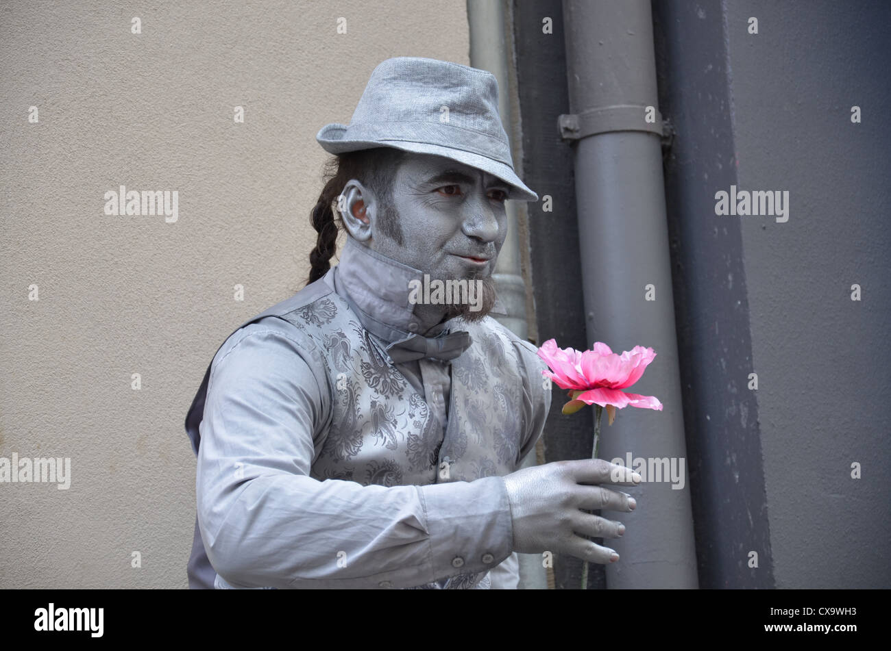 Un uomo in vernice argento tenendo un rosa in mano Foto Stock