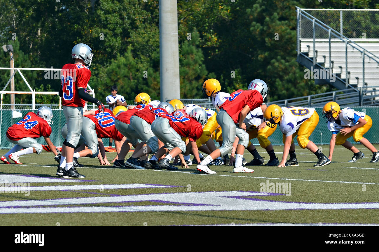 Squadre di 7° grado ragazzi sulla linea pronto per il quarterback per scattare la palla. Foto Stock