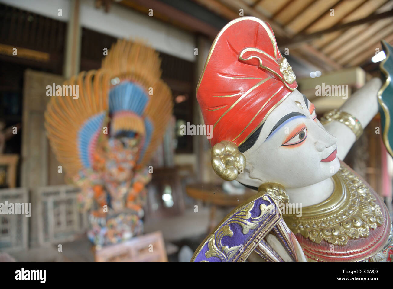Una statua balinese con la Garuda in legno in background; Ubud, Bali. Indonesia. Foto Stock