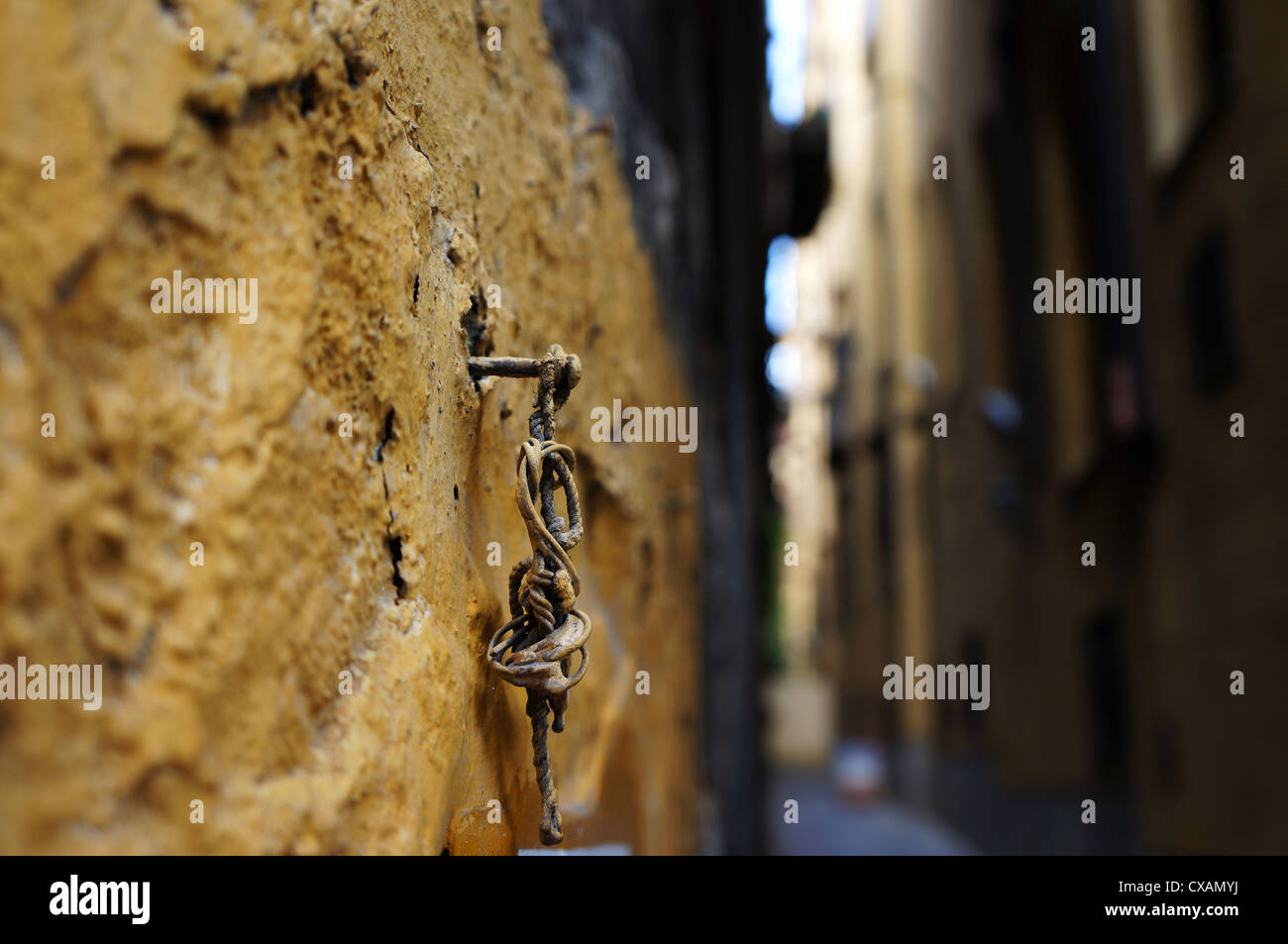 Vista di scorcio di una vecchia strada con un arrugginito perno fissato sulle pareti di tufo Foto Stock