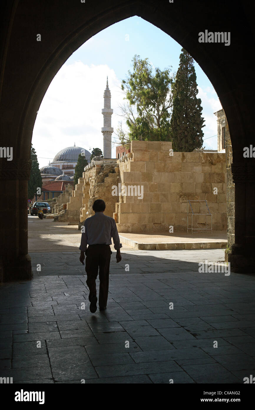 Rhodes, l'uomo corre attraverso un arco. Sullo sfondo, la Moschea di Solimano Foto Stock