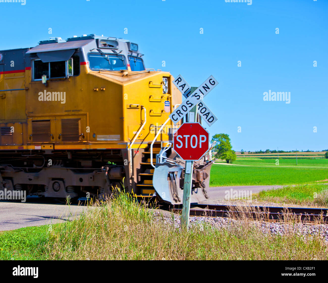 Un treno in movimento attraversare una strada in America rurale Foto Stock