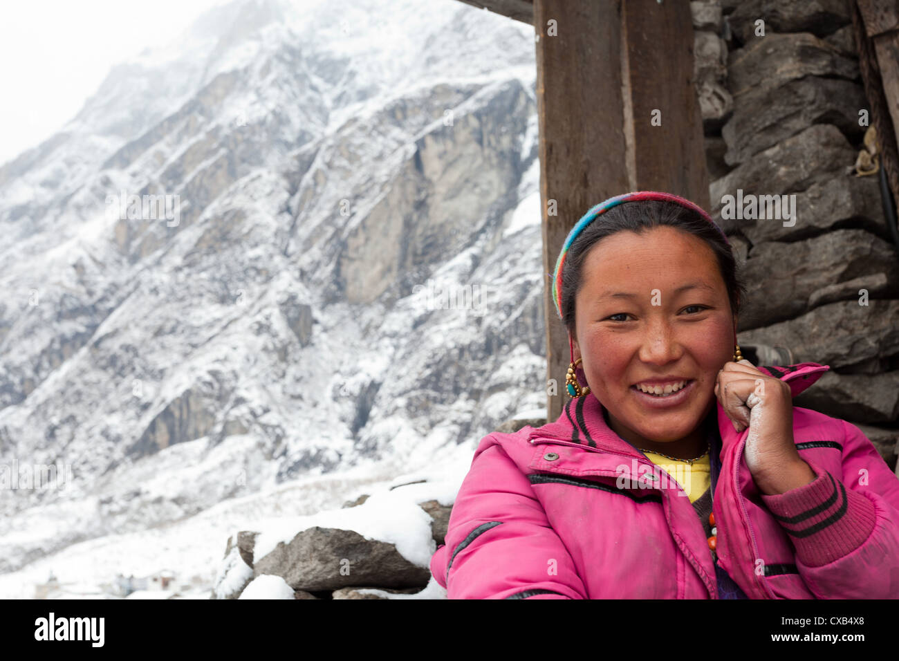 Giovani Tamang donna in piedi accanto a un muro di pietra e sorridente, Langtang village, Nepal Foto Stock