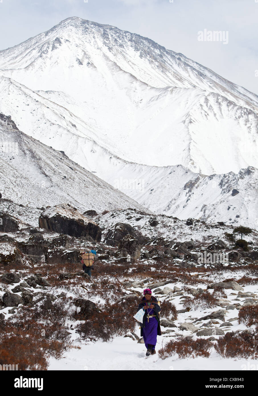 Tamang donna vestito in abiti tradizionali a piedi lungo un sentiero in mezzo alla neve lungo la valle di Langtang, Nepal Foto Stock