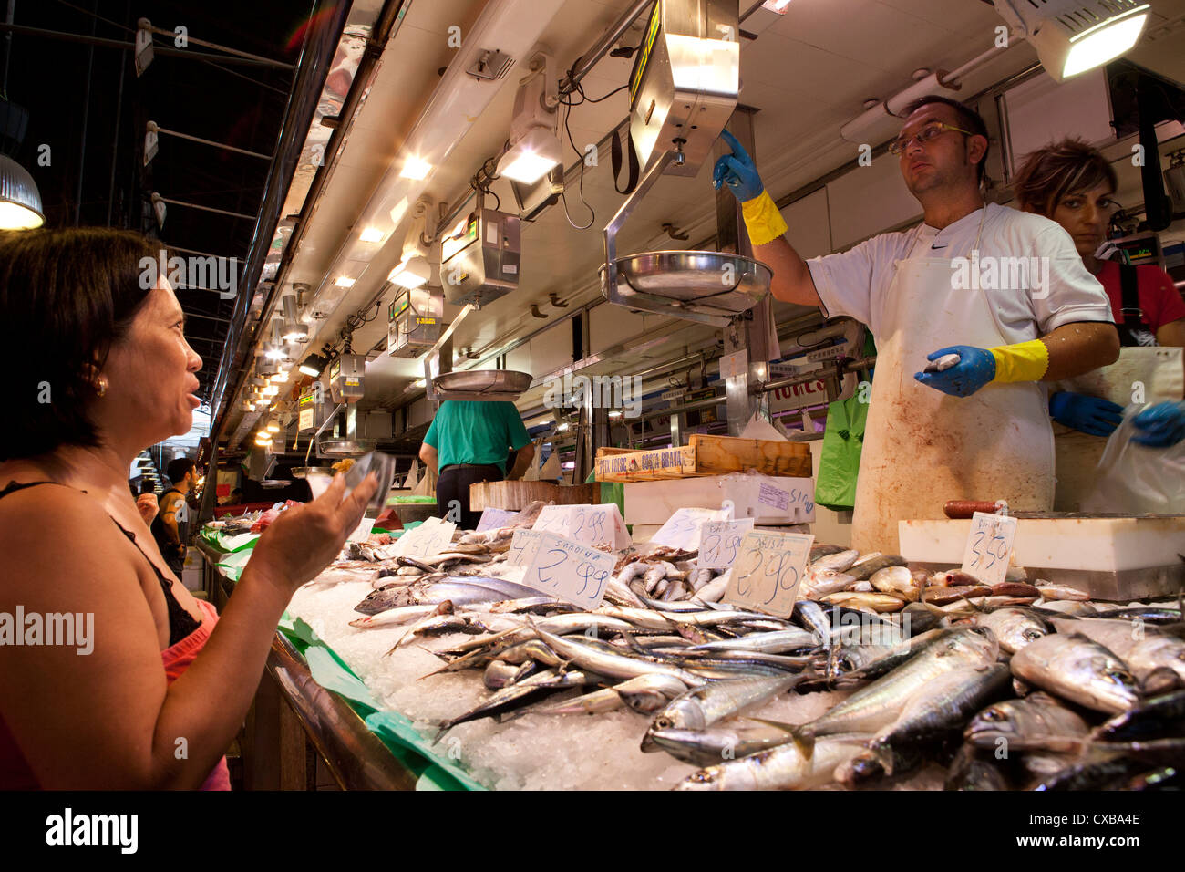 I clienti jockey di prestare attenzione in modo da poter posizionare il loro ordine con il pesce monger nel mercato La Boqueria di Barcellona. Foto Stock