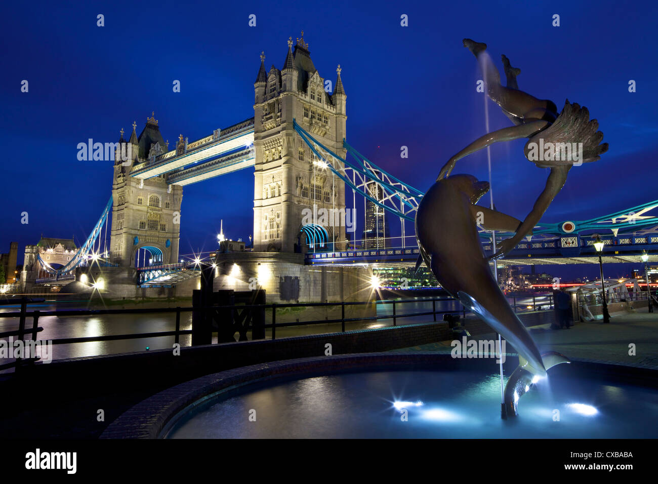 Ragazza con un delfino, statua di David Wynne, illuminata di notte nella parte anteriore del Tower Bridge, London, England, Regno Unito Foto Stock