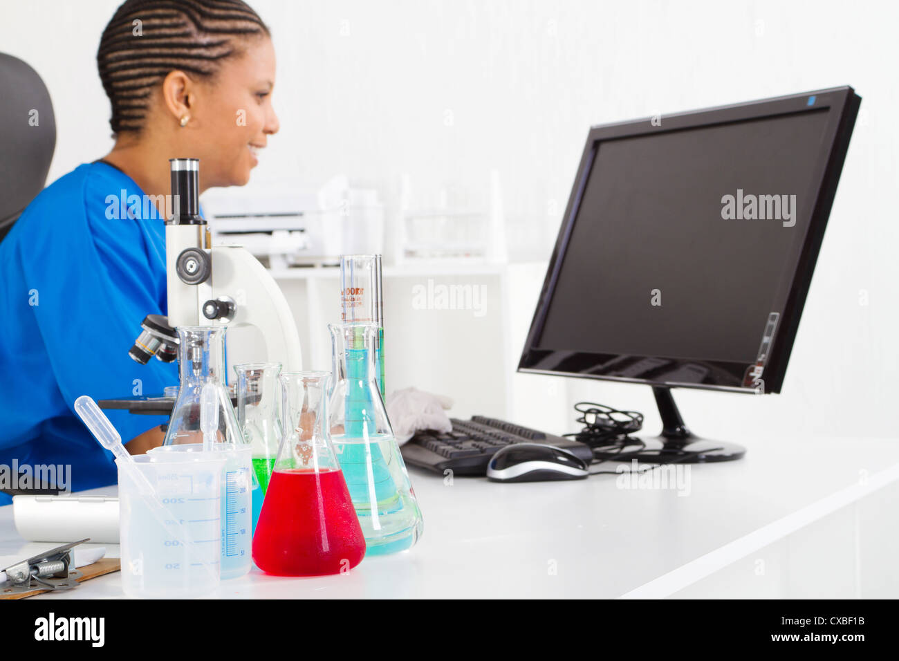 Africa femmina scienziato americano di laboratorio e di concentrarsi sul liquido nella parte anteriore Foto Stock