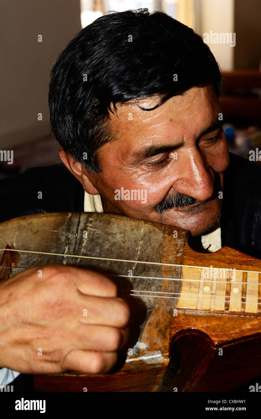 Un uomo tagiko riproduzione di un tradizionale strumento a corda. Foto Stock