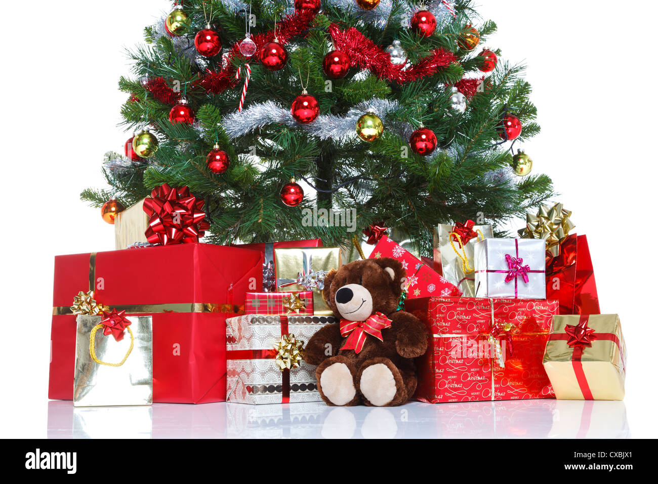 Albero di Natale decorato con baubles tinsel e circondato da regalo presenta e un orso di peluche Foto Stock