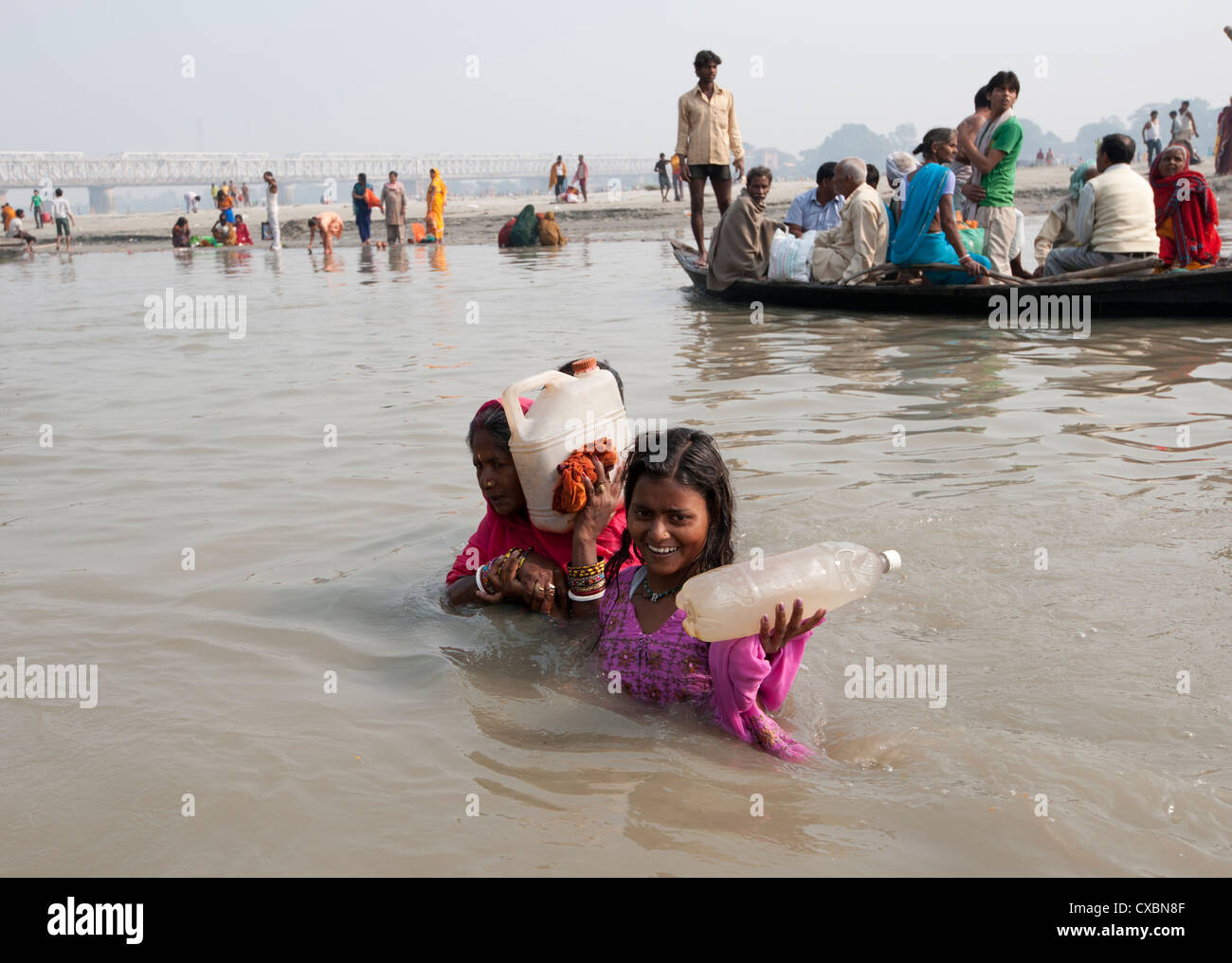 Madre e figlia guada il fiume Gange tenendo le bottiglie di Santo Gange acqua, Sonepur, Bihar, in India, Asia Foto Stock