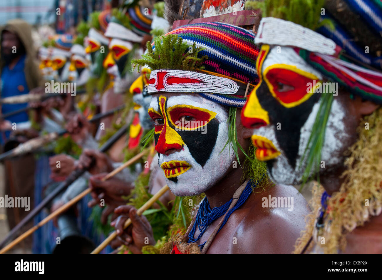 Vestiti in maniera colorata e il volto dipinto di tribù locali per celebrare il tradizionale cantare cantare nelle Highlands di Papua Nuova Guinea Foto Stock