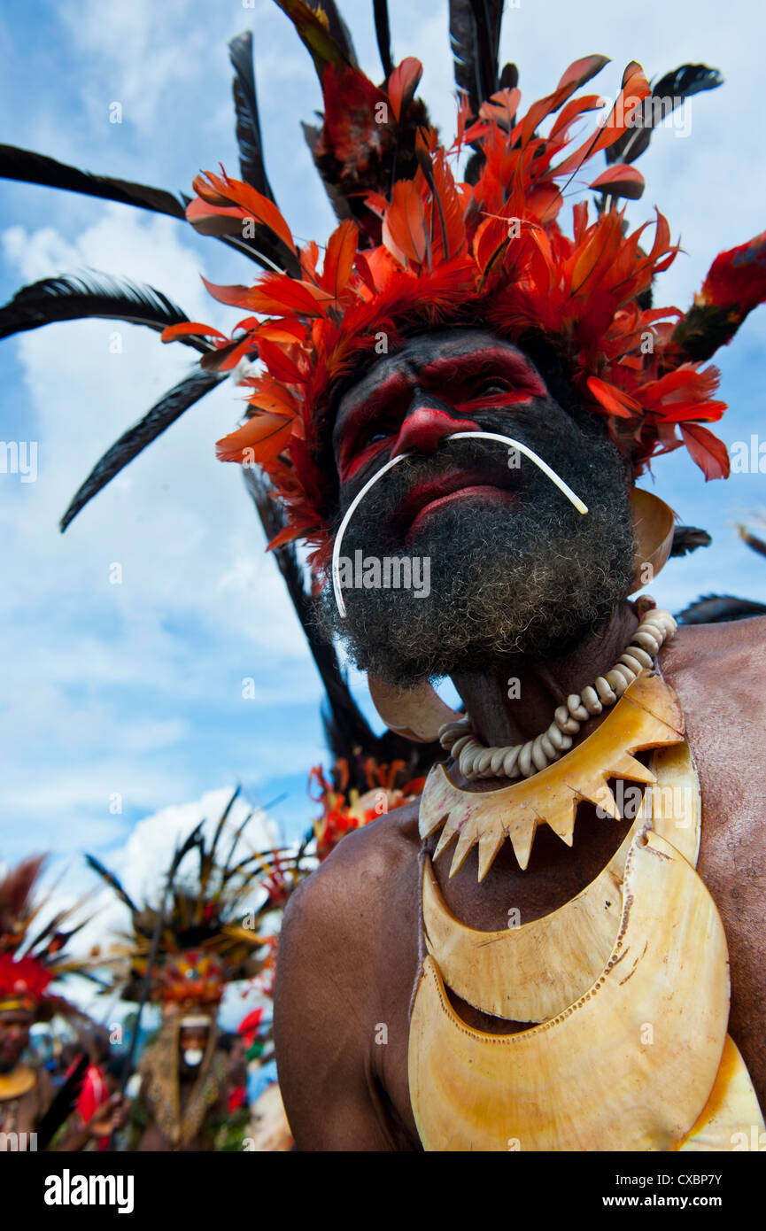 Vestiti in maniera colorata e la faccia dipinta tribesman locale per celebrare il tradizionale cantare cantare nelle Highlands di Papua Nuova Guinea Foto Stock