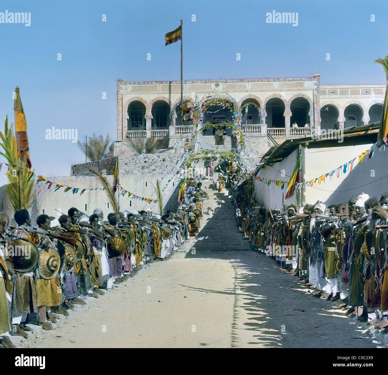 Vista colorata di capi e dignitari, con scudi e fucili, che costeggiano l'ingresso al luogo della cerimonia di incoronazione per l'imperatore etiope Haile Selassie i, Addis Abeba, Etiopia, 1930. (Foto di Burton Holmes) Foto Stock