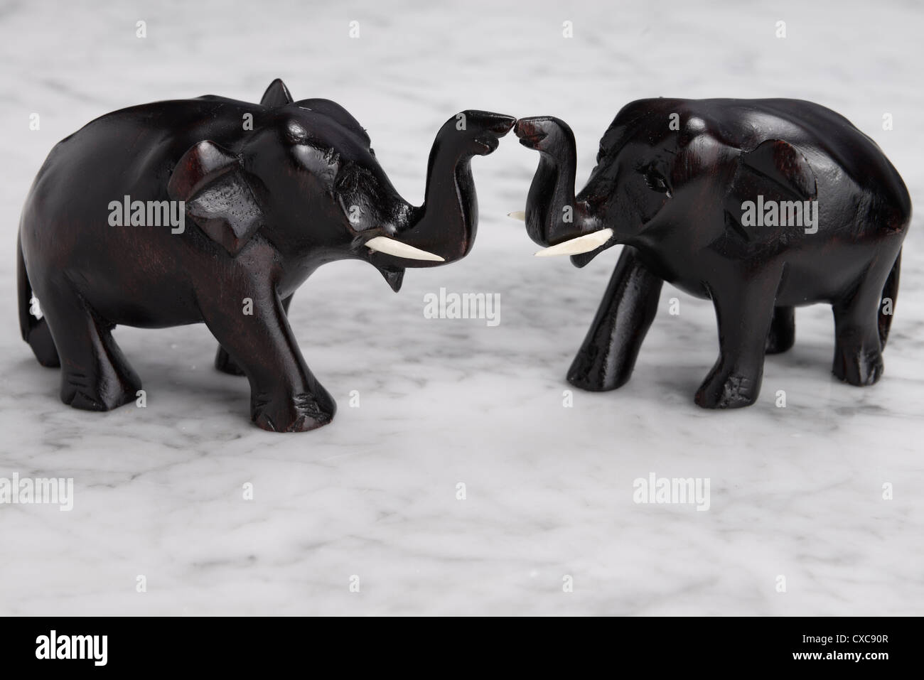 Due di legno intagliato elefanti con tronchi di toccare e sollevata sulla tavola di marmo a significare la buona fortuna Foto Stock