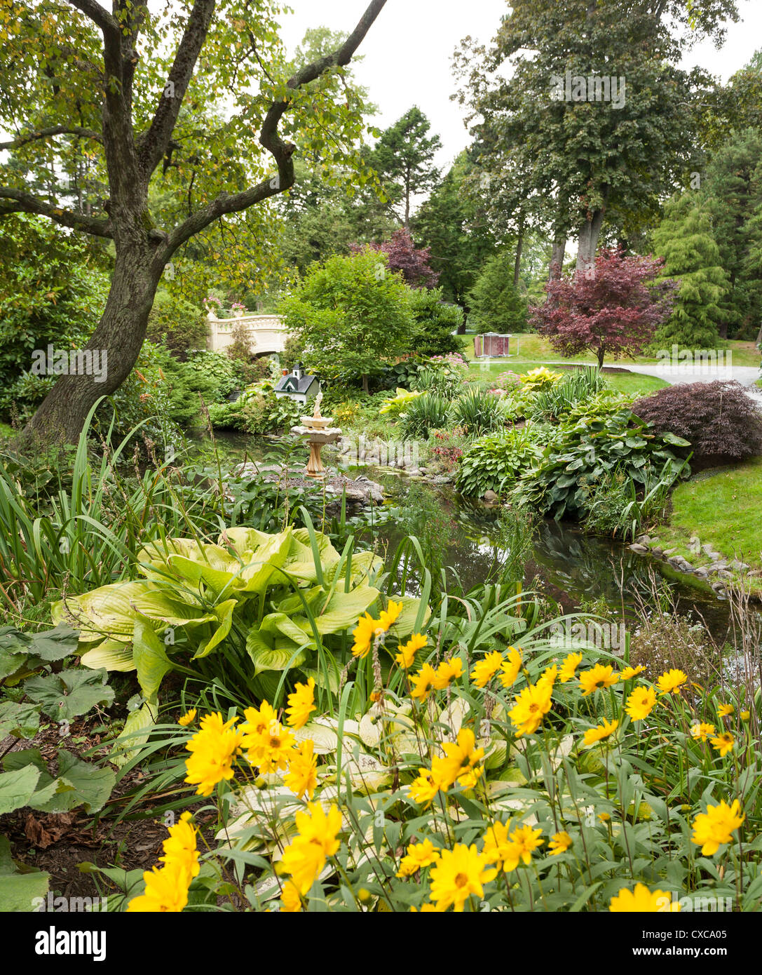 Lussureggianti fiori di primavera a Halifax giardini pubblici. Una fontana e un mini house includono in questa vista di dettaglio lungo un flusso Foto Stock