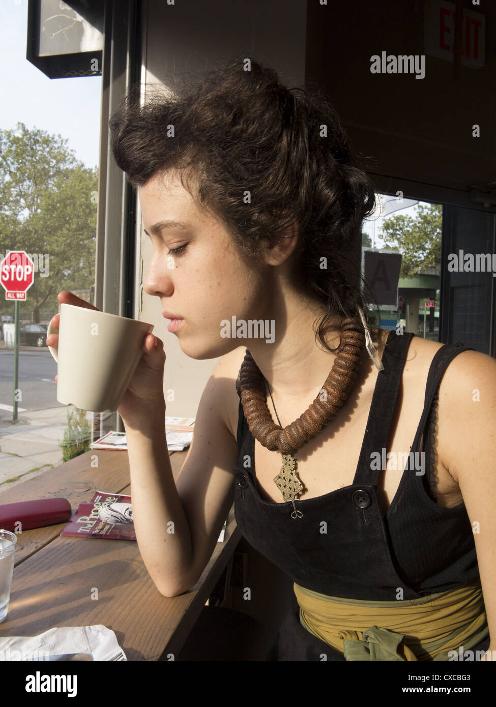 Giovane donna meditando qualcosa su una tazza di caffè in uno dei bar di Brooklyn, New York City. Foto Stock