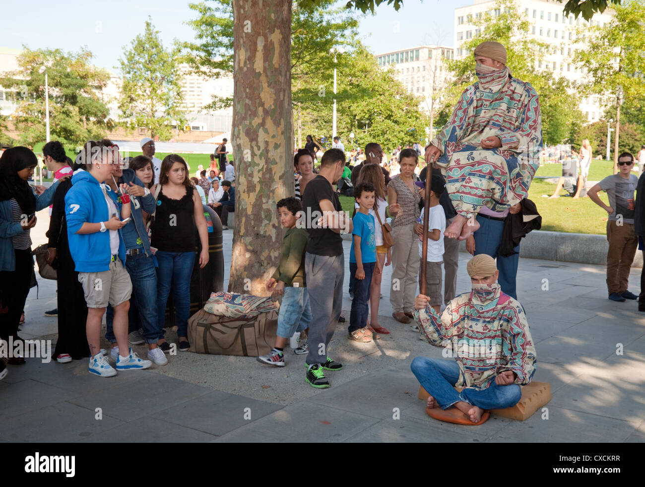 La gente a guardare gli artisti di strada facendo un illusione di levitazione trucco, South Bank di Londra REGNO UNITO Foto Stock