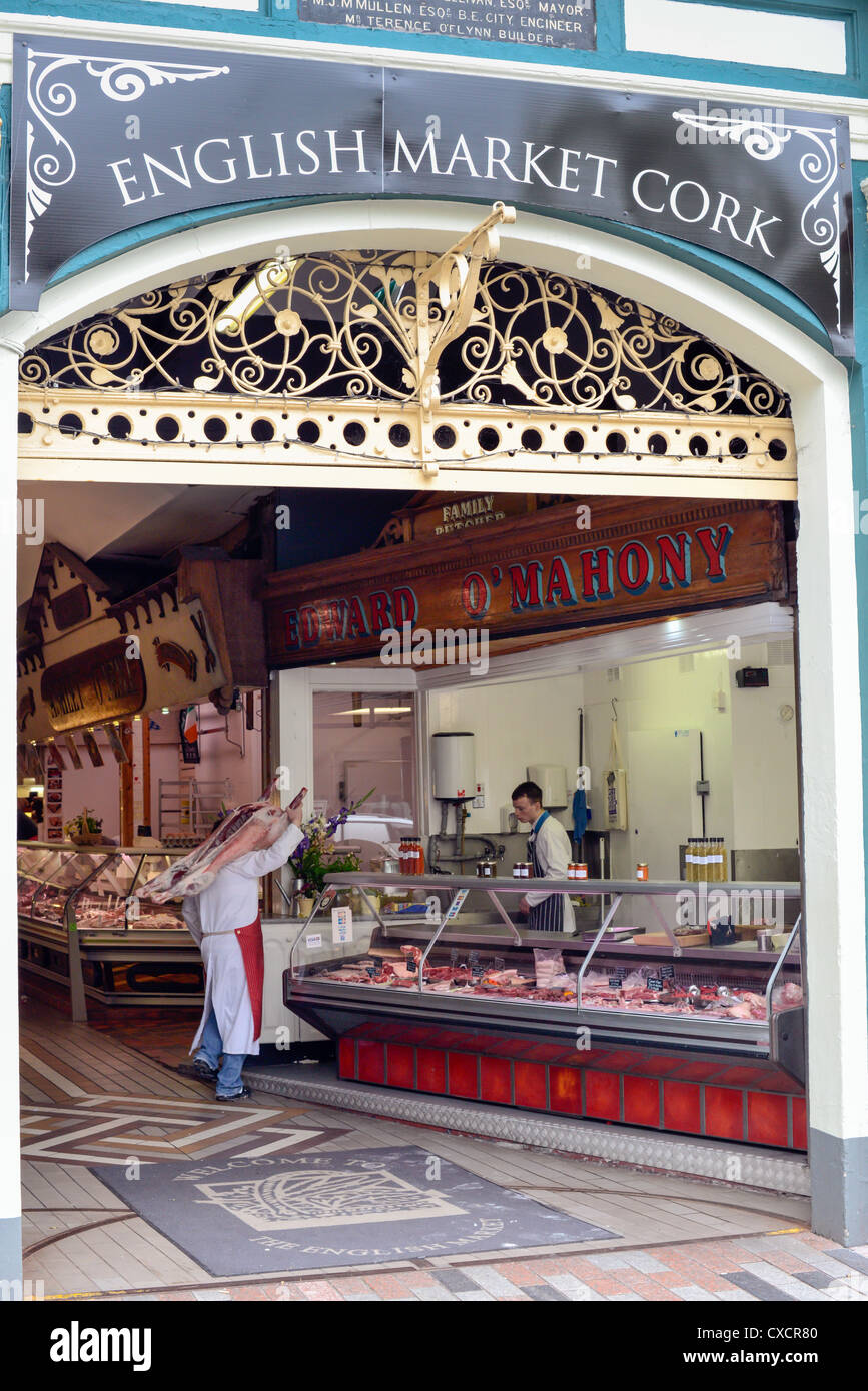 Un macellaio con un intero sopra la sua spalla al mercato inglese, la città di Cork, Repubblica di Irlanda. Foto Stock