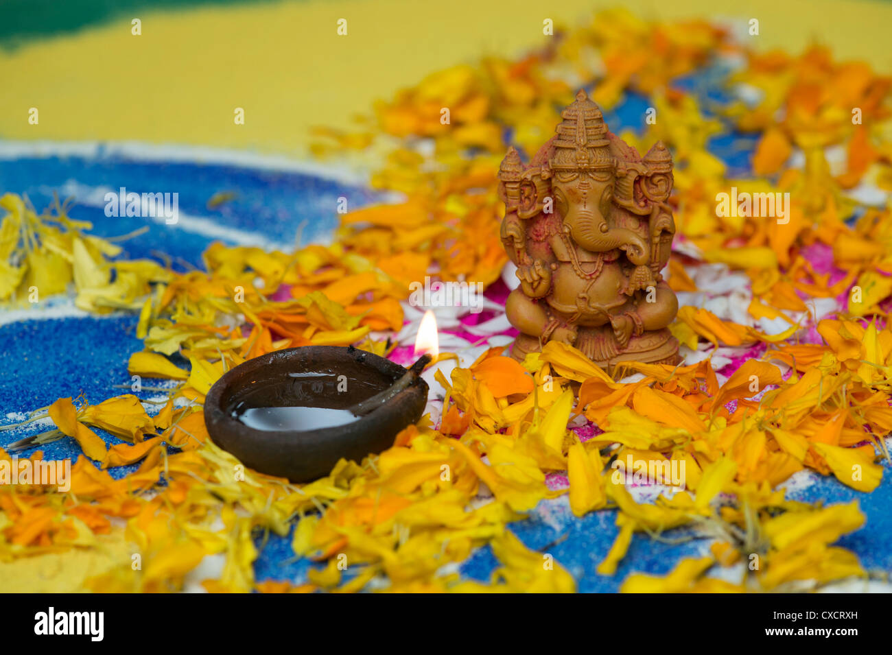 Elefante indù Dio. Signore Ganesha statua con lampada a olio e petali di fiori su un Indiano Rangoli Foto Stock