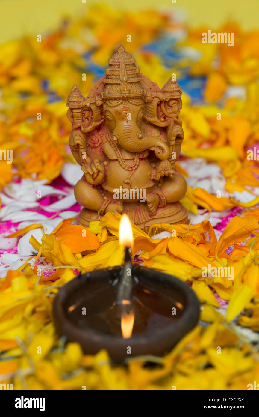 Elefante indù Dio. Signore Ganesha statua con lampada a olio e petali di fiori su un Indiano Rangoli Foto Stock